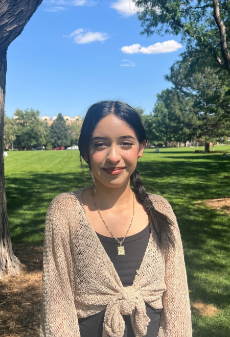 Daniela posing for a photo outside at a park with trees. 