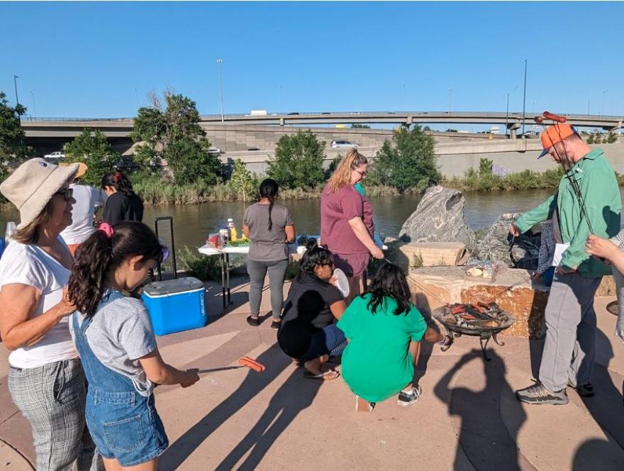 People preparing food outside by a river. 