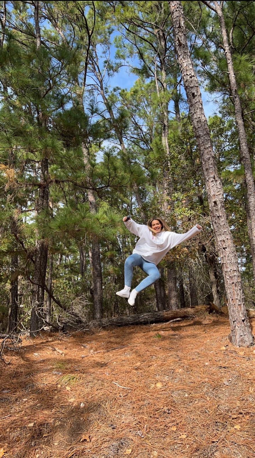 Honor jumping while posing for a photo in a forest. 