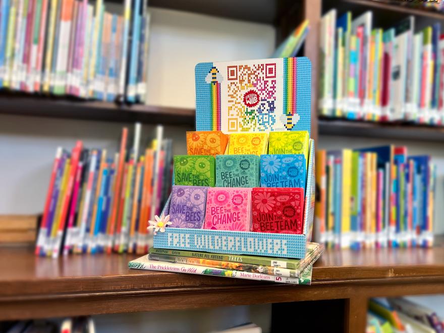 Point of sale display with colorful wildflower seed packets in a library. 