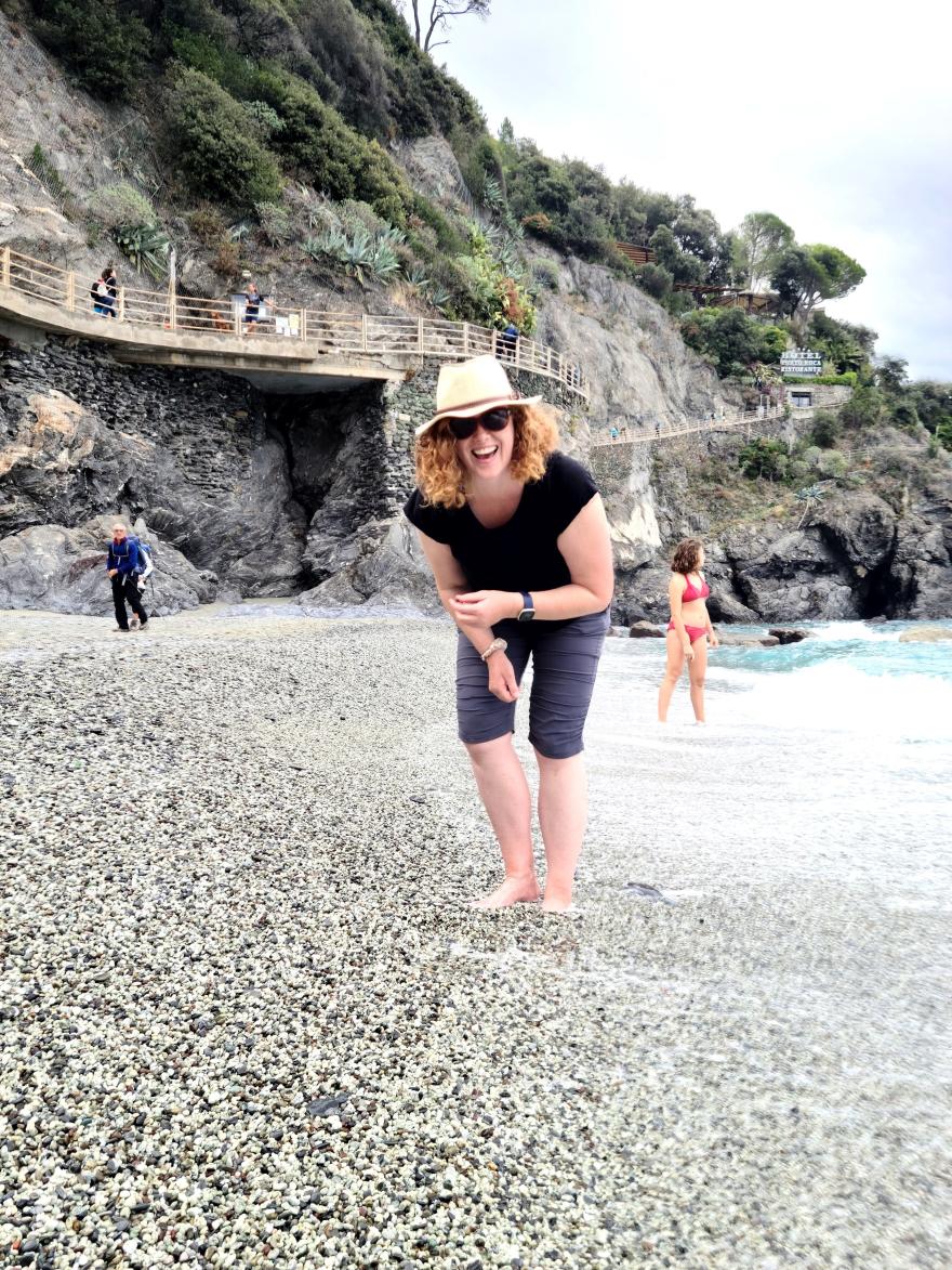 Amber Shanklin on a beach wearing a hat, smiling at the camera