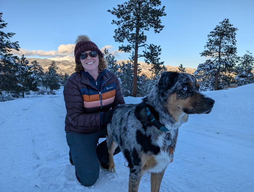 Amber Shanklin posing for a photo with her dog on a wintry snowy trail.