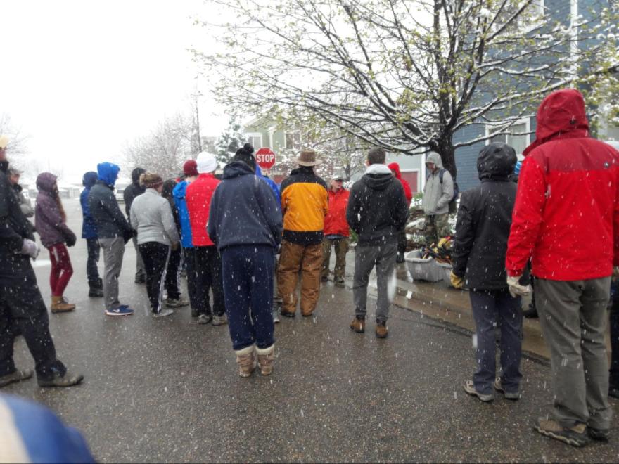 Shot of a group of volunteers during a light snowy winter day, taken from the back. 