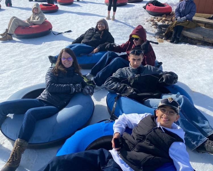 Taysen, Bella, and fellow Groundwork Denver youth enjoy tubing on a mountain adventure.